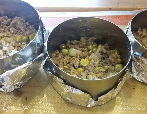 В кондитерские кольца, обернутые фольгой, вначале выкладываем фарш с зеленым горошком.