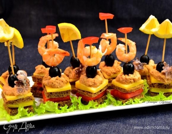 Собираем наши канапе как душа пожелает! У меня это хлеб, перец, хлеб, сыр, паштет из тунца ТМ «Магуро». На шпажку накалываем оливку, креветку и далее шпажку ставим в канапе. Также украсим наше канапе смешными осьминожками! :)