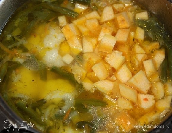 В кастрюлю с пассерованными овощами влить воду, всыпать стручковую фасоль, соцветия цветной капусты и кабачок, порубленный кубиками. Посолить. Варить 15–20 минут, накрыв крышкой.