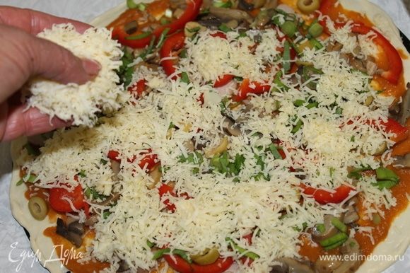 Сверху накройте пиццу натертым сыром и отправьте ее выпекаться в горячую печь до готовности.