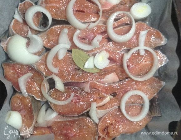 Рыбу нарезали (тут горбуша, но медицинский факт — любая), на сковородку — пергамент для запекания (создаст нужный для жарки, но не для пригорания слой), на пергамент — соль крупного помола и лук полукольцами, уложили рыбу кусками на лук, посолили, поперчили, лук сверху, лавровый лист. Маслом растительным сбрызнули каждый кусочек, стараясь мимо не проливать.