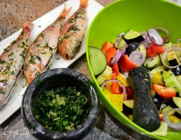 Готовим маринад для рыбы и овощей: имбирь, чеснок мелко натираем и в ступку. Туда же — измельченную зелень и специи. Все хорошенько растолочь, добавить масло, сок лимона. Из нескольких ароматов создаем один! Все хорошенько перемешиваем. Барабульку хорошенько со всех сторон обмазываем соусом и оставляем на 30 минут. А в это время нарезать овощи и полить соусом, как и для рыбы, дать пропитаться.