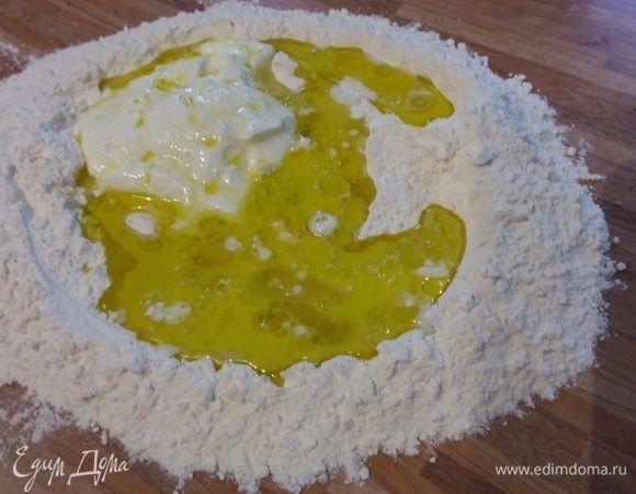 Тесто я замешивала прямо на столе. Муку смешать с разрыхлителем, солью и сахаром. В горке муки сделать лунку, в нее добавить йогурт, яичный белок (желток понадобится для смазки), влить молоко и оливковое масло. Замесить тесто. Долго месить не надо.