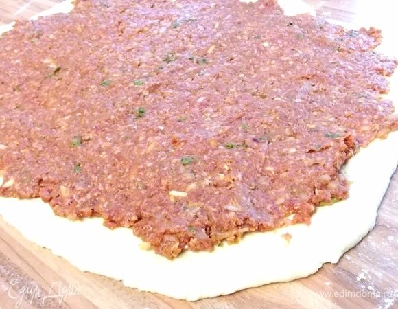 На припыленной мукой поверхности раскатать тесто в прямоугольник, выложить и разровнять фарш.