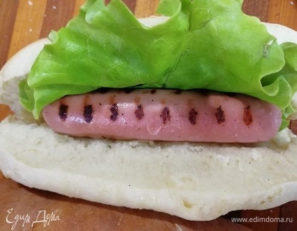 Укладываем листик салата, сосиску. По желанию, добавьте корейскую морковь, помидор, сыр.