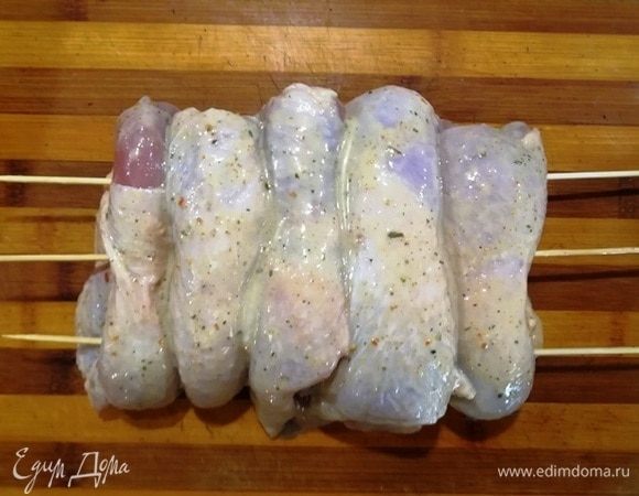 Вынимаем из маринада куриные бедрышки. Выкладываем рядком на доску и протыкаем шпажками.