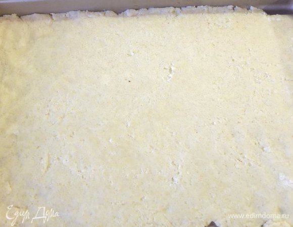 Отдохнувшее тесто делим на две равные части. Тонко раскатываем одну часть и выкладываем ее на противень (размер моей формы — 23х32 см), смазанный сливочным маслом. Я раскатывала на силиконовом коврике, а потом переносила на противень.