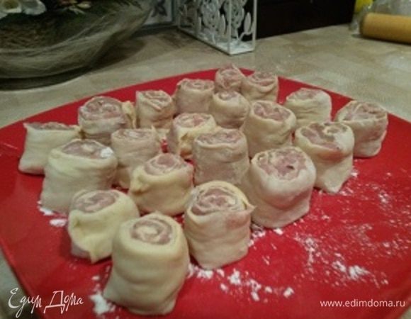 Разрежьте рулет на равные кусочки острым ножом. На остальную, раскатанную часть теста также выложите фарш, скрутите рулет и разрежьте. Пельменей получается много, так что часть можно заморозить. Теперь приготовим соус, в котором будем тушить наши ленивые пельмени.