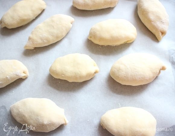 Положить пирожки на противень, застеленный пекарской бумагой.