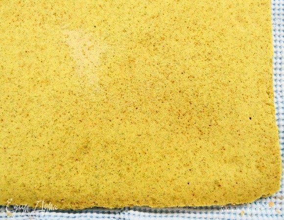 Готовый, еще горячий бисквит переворачиваем на чистое кухонное полотенце и снимаем пергамент. Переворачиваем бисквит и сворачиваем вместе с полотенцем в рулет. Охлаждаем до комнатной температуры.