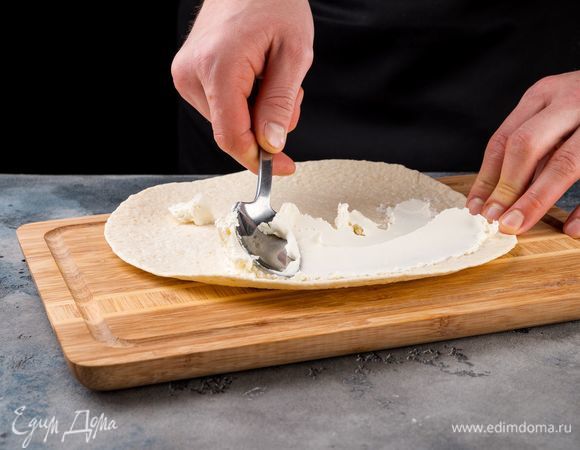 На рабочей поверхности разверните лаваш. Смажьте его равномерно сливочным сыром.