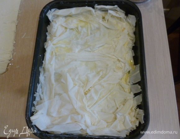 Выкладывать листы теста в форму так, чтобы немного оставались свисать края. Каждый слой-два смазывать растопленным маслом. Выложить так половину теста.