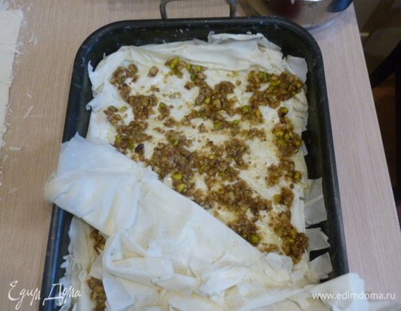 Выложить половину начинки. Распределить по всей форме. Выложить оставшуюся часть теста, смазывая каждый слой-два.