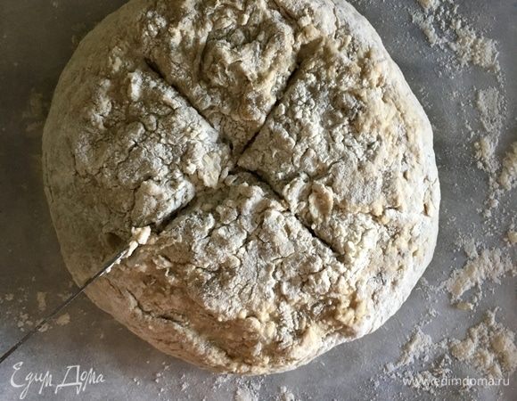 Противень застелить бумагой для выпечки. Немного припылить бумагу мукой. Перенести шар на бумагу, сверху и по бокам немного посыпать мукой и сделать ножом крестообразный разрез на верхушке хлеба. Выпекать примерно 30–40 мин. до готовности. При постукивании готовый хлебушек должен издавать полый звук.