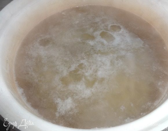 В кастрюлю налить необходимое количество воды, положить картофель. Довести до кипения, снять пену и варить почти до готовности. Немного посолить.