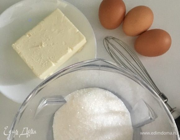 В другую емкость отмерить сахар. Подготовить три яйца и сливочное масло. Масло должно быть непременно мягкое, растаявшее при комнатной температуре.