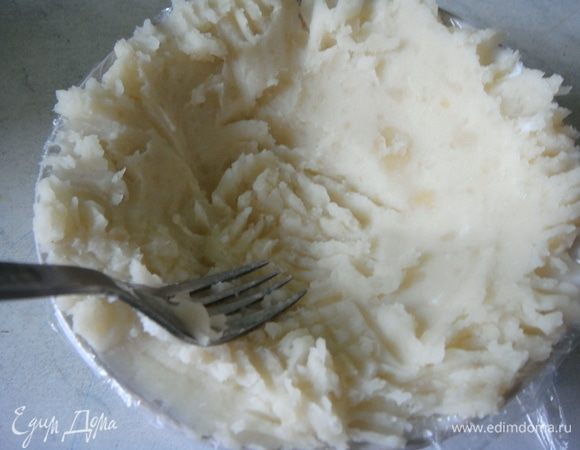 Берем небольшой салатник, застилаем его пищевой пленкой, так чтобы концы немного свисали. Выкладываем примерно 5 ст. л. картофеля и распределяем его по дну и стенкам.<br />
 