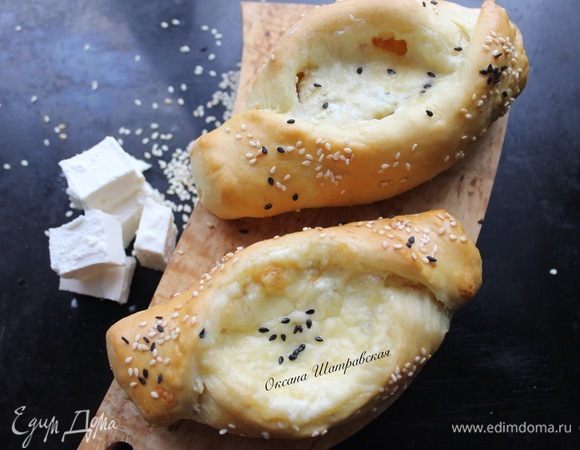 Поднявшееся тесто перенести на припыленную мукой поверхность и обмять. Сформировать шарики. Раскатать или сформовать лепешки эллиптической формы длиной около 15 см. Приподнять и присобрать края, чтобы начинка не растекалась. Уложить на смазанный маслом противень на значительном расстоянии друг от друга. Распределить начинку, выложив ее в центр каждой лепешки и посыпав маленькими кусочками масла. Дать лепешкам подойти в течение 20–30 минут. Духовку тем временем нагреть до 180°C. Выпекать лепешки до готовности теста и золотистого цвета примерно 20–25 минут.