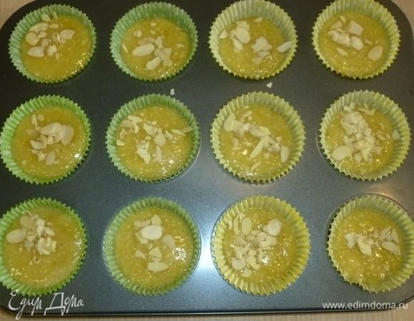 Разложить тесто по формам, заполняя их на 3/4, посыпать миндльными лепестками и выпекать 15–20 минут до золотистого цвета.
