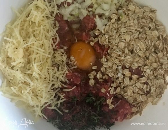 Теперь в миске соединяем непосредственно говяжий фарш, порубленные мелко лук и чеснок, три столовые ложки овсяных хлопьев ТМ «Националь», натертый сыр, листики тимьяна и разбиваем одно яйцо. Соль и свежемолотый перец по вкусу, как и всегда. И перемешиваем до однородности. Но долго перемешивать не советую, чтобы тефтельки получились более нежными внутри и воздушными.