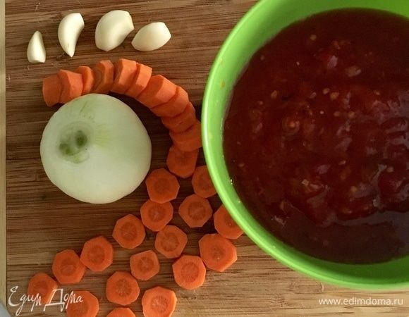 А тем временем займемся любимым томатным соусом. У меня абсолютно классический вариант его приготовления. То есть одна белая луковица, чесночек (пару или тройку зубчиков), небольшая морковка. Лук и чеснок мелко порубить. Морковь я нарезала кругляшами. Томатный соус без томатов не бывает. Значит, берем помидоры. У меня помидоры, рубленные в собственном соку, из собственных домашних заготовок.