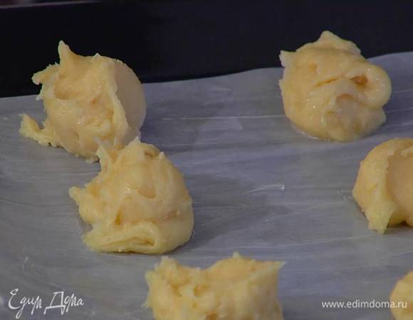 Противень выстелить бумагой для выпечки, смазать ее оставшимся сливочным маслом и выложить тесто столовой ложкой, каждый раз окуная ее в холодную воду, чтобы тесто не прилипало.