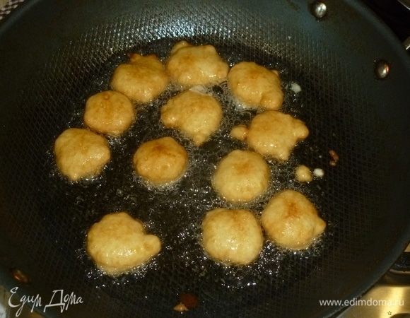 В глубокой сковороде разогреть масло. Количество масла указано примерно, главное, чтобы уровень был не менее 1–1,5 см. Чтобы проверить готовность масла, можно капнуть в него немного теста. Если оно начинает быстро обжариваться, масло готово. Чайной ложкой выкладывать тесто в масло. Можно помогать себе второй чайной ложкой. Обжаривать пончики со всех сторон до золотистого цвета.