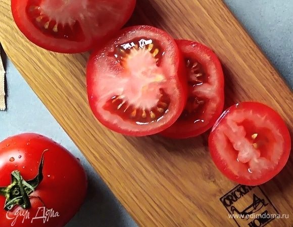 Духовку разогреть до 220°C. Помидоры нарезать, оставшийся чеснок почистить. В форму для запекания уложить курочку, вылить маринад. Добавить помидоры и чеснок. Запекать до готовности, около 30 минут.