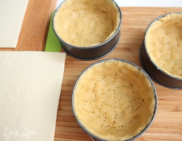 Поместить раскатанное тесто в формочки, закрыть им дно и борта формочек, смазанных сливочным маслом. Проколоть вилкой, убрать в холодильник. Достать из морозильной камеры слоеное бездрожжевое тесто, дать ему немного постоять при комнатной температуре.