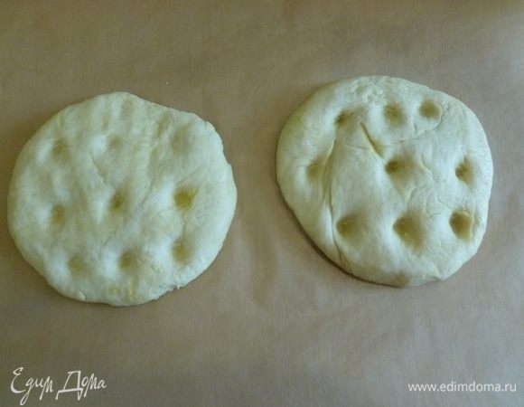 Духовку разогреть до 200°C. Тесто разделить на 2 части, сформировать две лепешки, переложить на застеленный пергаментом противень, сделать кончиками пальцев углубления.