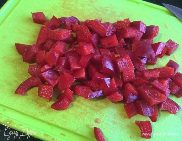 У болгарского перца удалите семена и также нарежьте. Выложите перец и морковь на сковороду и жарьте примерно 3–4 минуты.