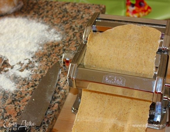 Достать тесто из холодильника, отрезать от него примерно 1/6 часть, сплющить с помощью пальцев в прямоугольную форму, и начать прокручивать через ролики машинки. Прокрутив один раз, вы получите широкую по ширине, и тонкую по толщине ленту из теста. Сложить ленту вдвое, повторить процедуру прокрутки еще 2 раза. Если вы пользуетесь скалкой, то процедура та же самая. Приготовить несколько лент (необходимое количество), откинуть на поверхность, присыпанную мукой. Оставшееся тесто заверните в пленку, уберите в холодильник.