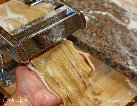 Установить ручку машинки в ту часть, где режется паста. Брать ленту по одной, пропускать через «ножи» для тальятелле. Если же вы работаете скалкой, то каждую ленту из теста надо скрутить в короткую трубочку и нарезать ножом на толщину тальятелле (или любую, какую вам нравится). Каждую порцию тальятелле обваляйте сразу в муке, чтобы избежать склейки.