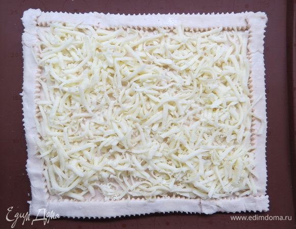 Сыр сулугуни натереть на крупной терке, распределить по поверхности теста.