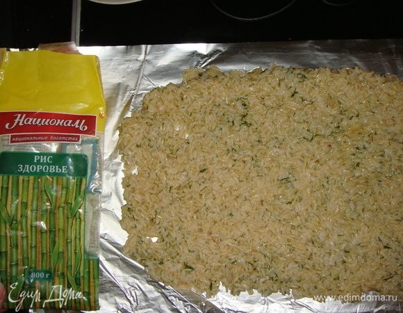К рису добавить яйцо и мелко порубленную зелень. Хорошо все перемешать. Выложить рис на фольгу и разровнять ложкой.