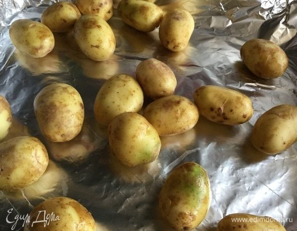 Молодой картофель тщательно вымойте щеткой. Застелите противень фольгой и выложите картофель.
