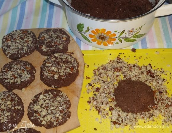 Из теста скатать небольшие шарики, расплющить их до размеров печенья и окунуть одной стороной в молотые орехи.