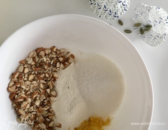 В чашу к муке, сахару, соли и разрыхлителю добавить порубленный миндаль и цедру лимона. Зерна кардамона освободить от оболочки, истолочь в ступке и добавить к сухим ингредиентам.