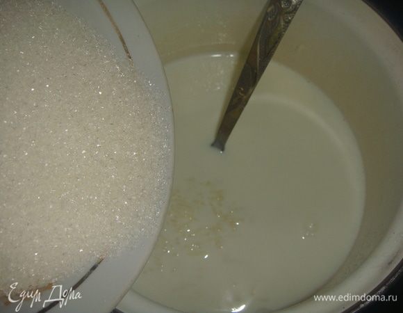 По мере уменьшения жидкости, влить остальное молоко в два этапа. Всыпать половину сахара.