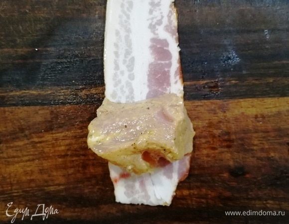 На полоску бекона выкладываем кусочек индейки и оборачиваем его.