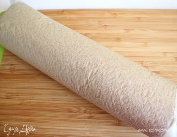 Горячий бисквит вместе с бумагой для выпечки свернуть в рулет, поместить на разделочную доску швом вниз. После остывания развернуть, снять бумагу.