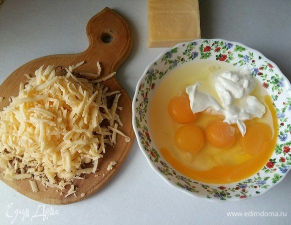 Подготовим заливку. Разбить 4 яйца, добавить к ним 2 ст. л. сметаны, перемешать. Добавить натертый сыр.