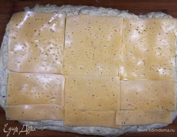 Растягиваем руками тесто в пласт и выкладываем пластинки сыра «Гауда». Можете взять плавленый сыр. Тоже будет вкусно.