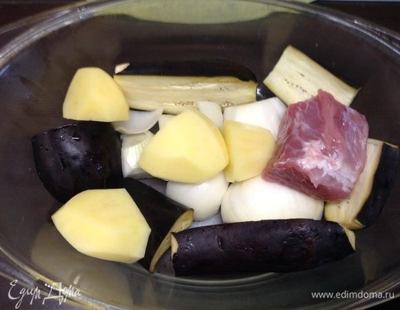 В посуду для запекания (у нас тут стеклянная) нарезали крупно-крупно лук, баклажаны, половину картофеля, буквально половинками или четвертинками. И начинаем укладывать плотно мясо.