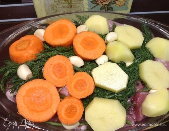 На мясо уложили весь укроп, на него зубчики чеснока, морковь очень крупными толстыми кольцами, картофель остальной так же, как и морковь.