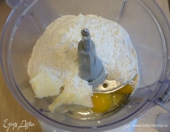 Добавить просеянную муку и щепотку соли. Прокрутить до состояния крошки, затем быстро замесить тесто. Если нет кухонного комбайна, то можно растереть все пальцами. Если тесто будет рассыпаться, то нужно добавить ложку холодной воды, чтобы удобнее было работать.