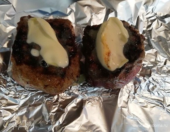 Обжаренную говядину перекладываем на фольгу. Выкладываем на каждый стейк по 1 ч. л. сливочного масла. Заворачиваем фольгу и отправляем стейки в разогретую до 200⁰С на 4 минуты. Вынимаем стейки из духовки. Разворачиваем фольгу и даем отдохнуть мясу 3 минуты.