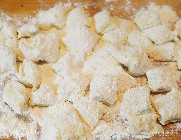 Положите полоски друг на друга и нарежьте на кусочки. Присыпьте мукой.