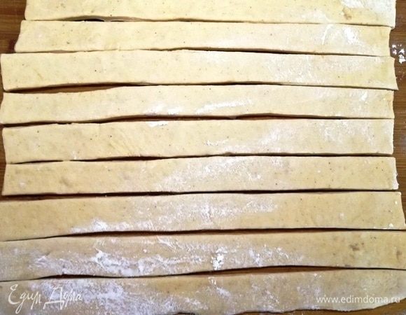 Половину теста раскатываем в тонкий пласт и нарезаем полосками около 2 см.