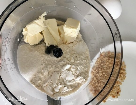 Начнем с приготовления песочной основы для пирога. Для нее в комбайне необходимо смешать муку, щепотку соли, чайную ложку сахара и холодное сливочное масло. Перемешать. Подготовить одно яйцо, и обжарить на сухой сковороде до золотистого цвета пару столовых ложек кедровых орешков.